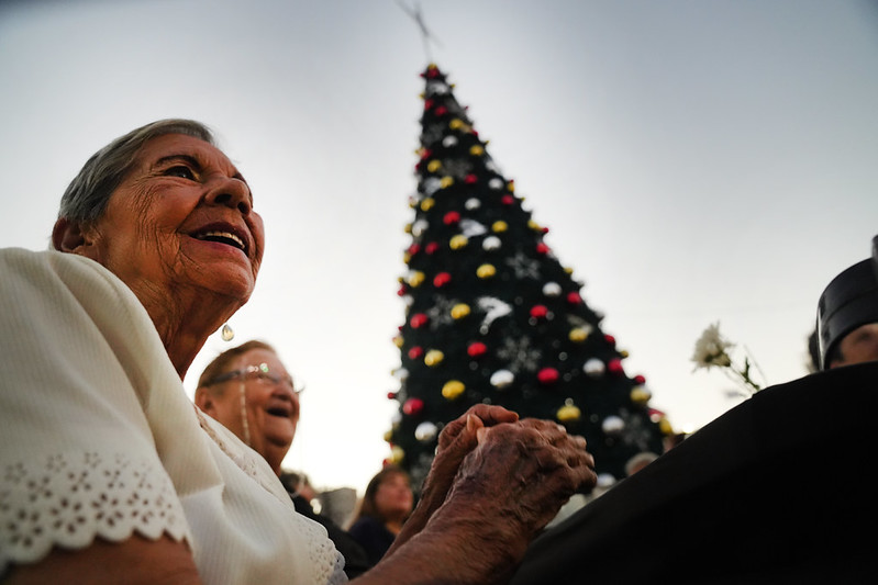 Personas mayores compartiendo frente a un &aacute;rbol de Navidad